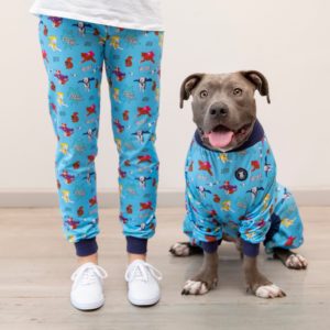 matching supper pebbles pitbull pajamas - picture of a pitbull sitting is his pajamas next to his human's legs with pajama pants